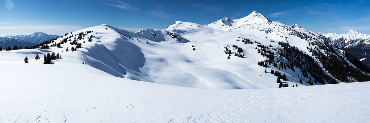 A rider on a snowmobile on a ridge above Trout Lake with the frozen valley below