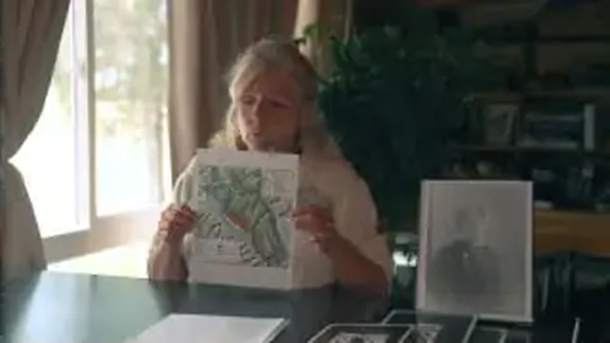 Still from the film: Jeanine of the Trout Lake Recreational Club holding the riding-area map